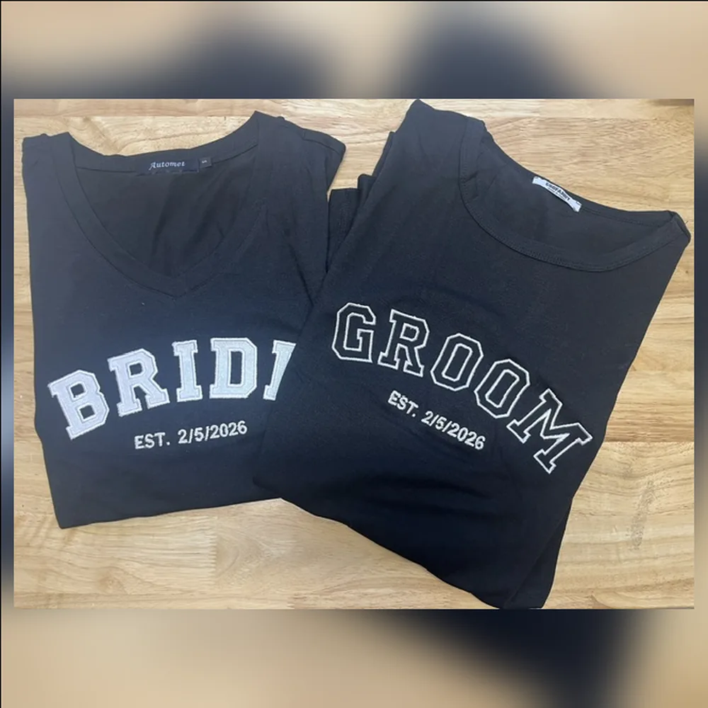 Black Bride and Groom tees with white varsity letters and EST. 2/5/2026 embroidered beside them.
