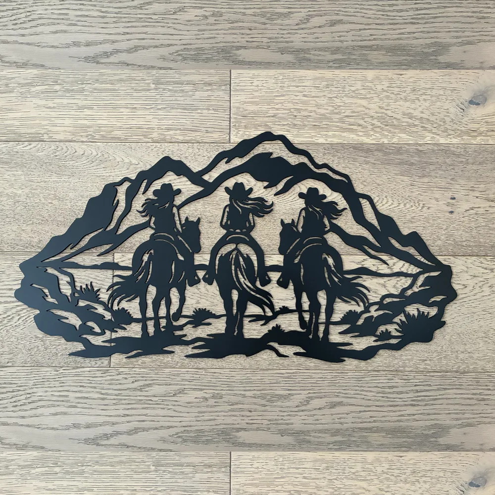 Black metal scene of three cowgirls on horseback riding toward the mountains.