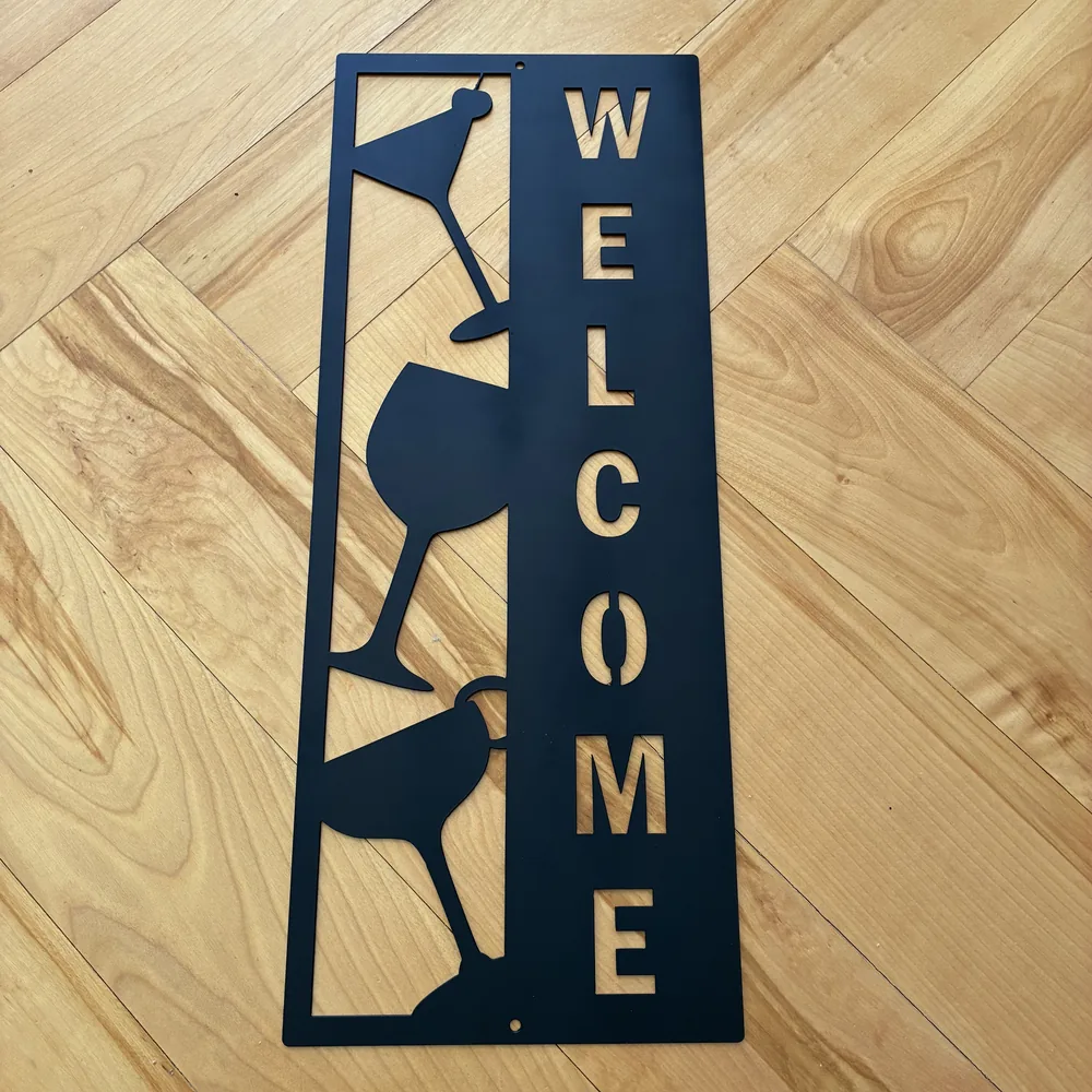 Black steel WELCOME sign with cocktail and wine glasses.