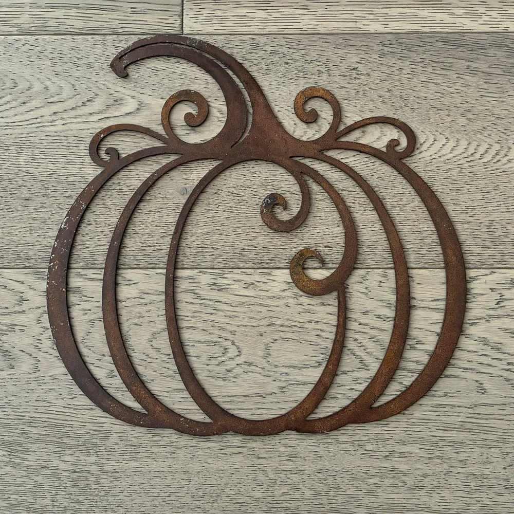 Rusted metal pumpkin made of curved bands with scrollwork.