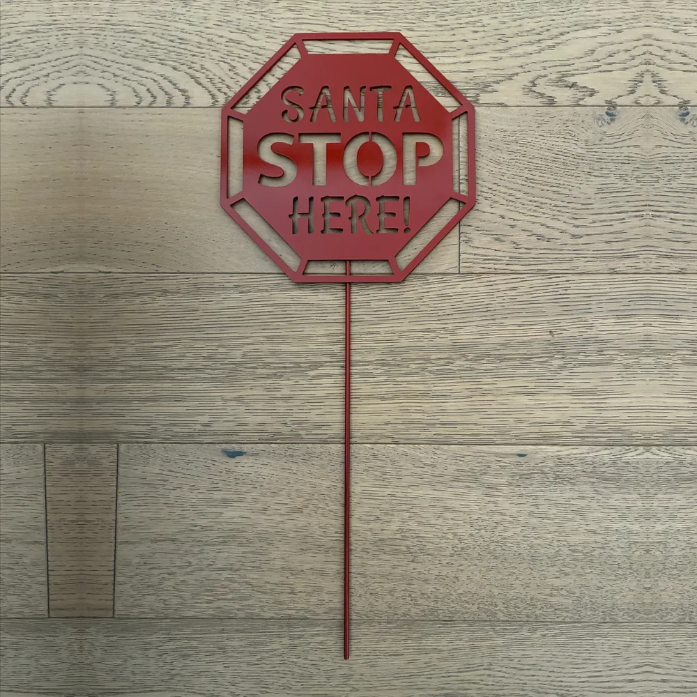 Red metal octagon sign reading SANTA STOP HERE on a single stake.