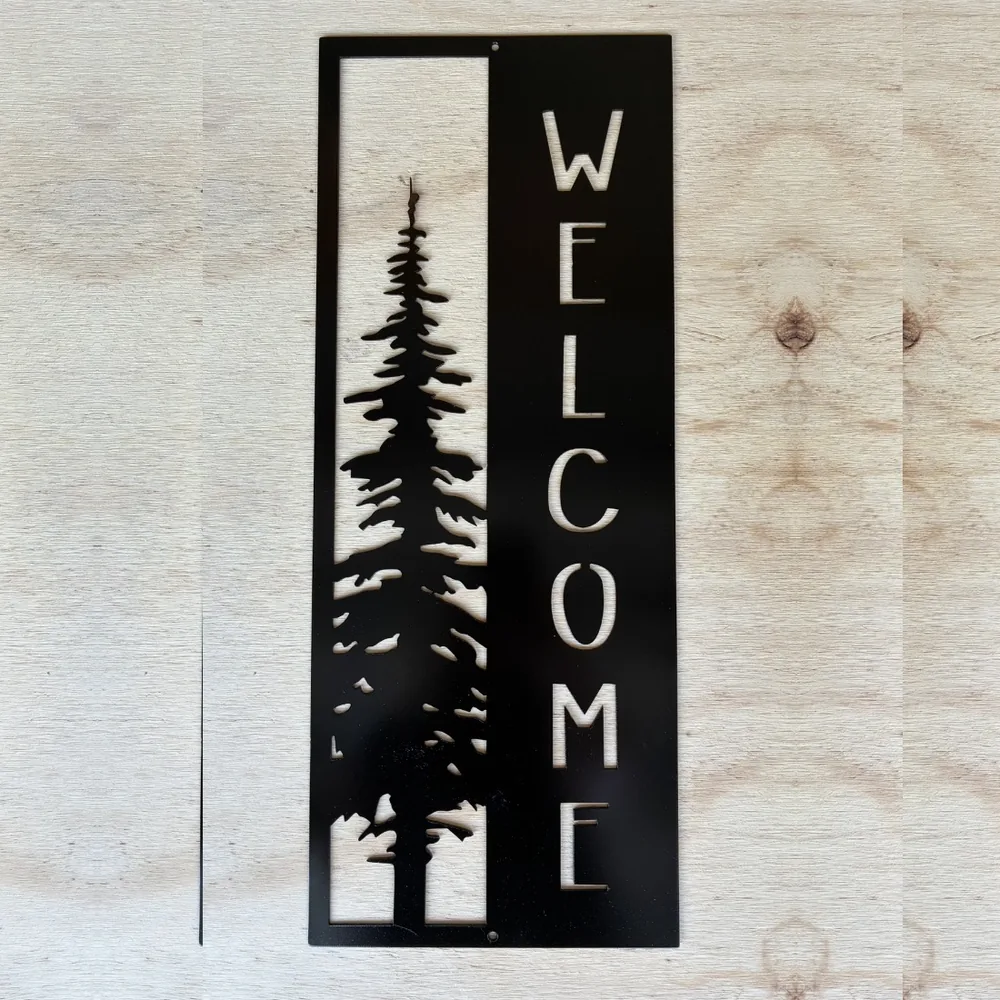 Black welcome sign with a tall pine tree cut from steel.